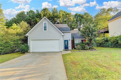 Traditional home featuring a garage, a front lawn, concrete driveway, and view of scattered trees