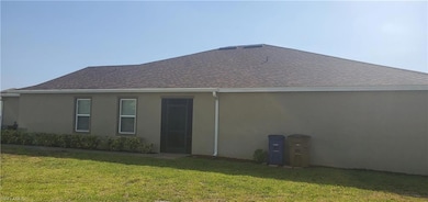 Back of house with stucco siding, a yard, and a sh