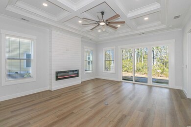 Unfurnished living room featuring ornamental molding, light wood-type flooring, a large fireplace, and coffered ceiling