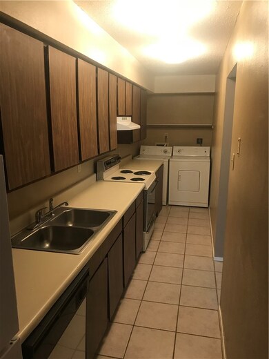 Kitchen with dishwashing machine, sink, light tile