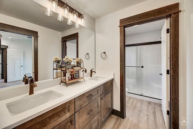 Bathroom with a stall shower, double vanity, and light wood-type flooring