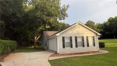 View of side of home featuring a yard, concrete driveway, and a garage