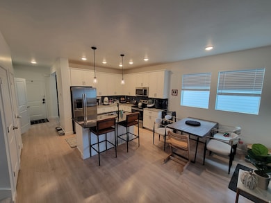 Kitchen featuring white cabinetry, stainless steel appliances, decorative light fixtures, decorative backsplash, and a kitchen island with sink