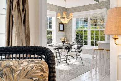 Dining space featuring wallpapered walls, light tile patterned floors, a notable chandelier, and a wealth of natural light