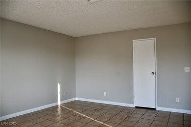 Tiled empty room featuring a textured ceiling and