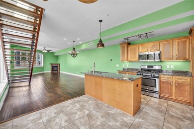Kitchen featuring a kitchen island, decorative light fixtures, stainless steel appliances, ceiling fan with notable chandelier, and light hardwood / wood-style floors