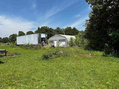 View of grassy yard featuring an outdoor structure and view of wooded area