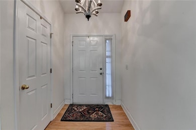 Foyer with a chandelier, light wood finished floors, and baseboards