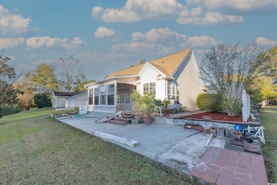 Back of property featuring a patio area, a yard, and a sunroom