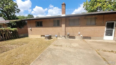 Rear view of property with a chimney, brick siding, a patio, and a lawn