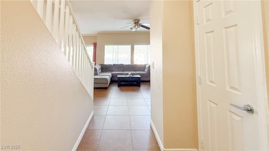Hall with a textured wall, light tile patterned floors, and ornamental molding