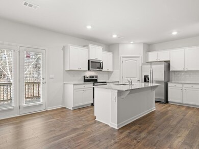 Kitchen featuring white cabinetry, stainless steel appliances, a breakfast bar area, light stone counters, and recessed lighting