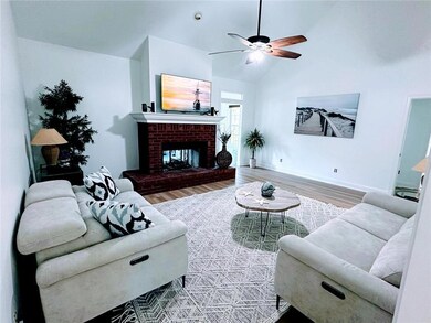 Living room featuring high vaulted ceiling, ceiling fan, a brick fireplace, and hardwood / wood-style floors