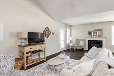 Living room featuring lofted ceiling, baseboards,