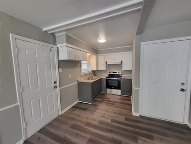 Kitchen featuring stainless steel range with electric stovetop, white cabinetry, light countertops, dark wood-style floors, and under cabinet range hood