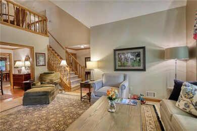 Living room with stairway, high vaulted ceiling, and wood finished floors