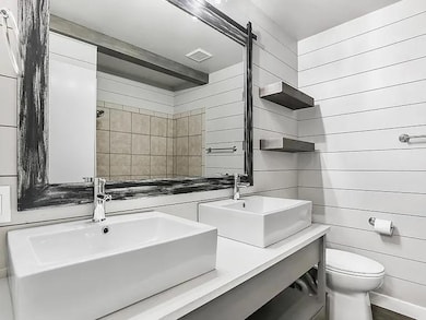 Bathroom featuring double vanity, a tile shower, and wooden walls