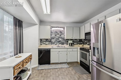 Kitchen featuring black appliances, a sink, light countertops, and healthy amount of natural light