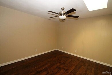 Spare room featuring dark wood-type flooring, baseboards, and ceiling fan