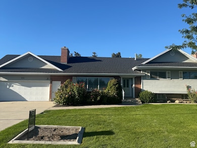 View of front of home featuring a front lawn, driveway, a garage, and a chimney
