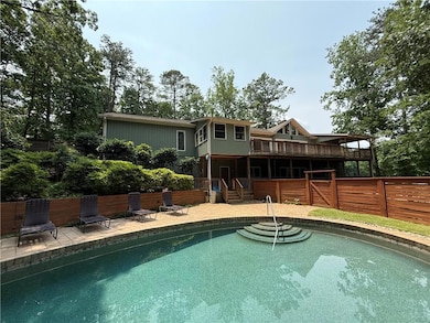 Rear view of house featuring a deck, an outdoor pool, and a patio