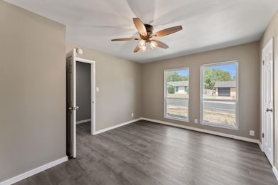 Empty room with dark wood-style floors and ceiling fan
