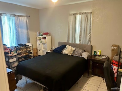 Bedroom with light tile patterned flooring and a textured wall