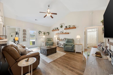 Living room featuring a ceiling fan, high vaulted 