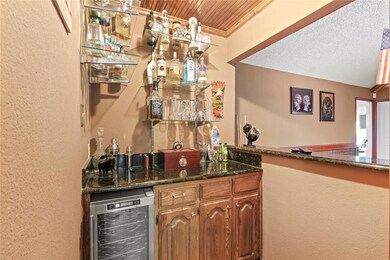 Bar featuring dark stone countertops, crown moldin