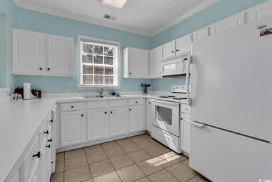 Kitchen with white appliances, light countertops, white cabinets, light tile patterned floors, and a textured ceiling