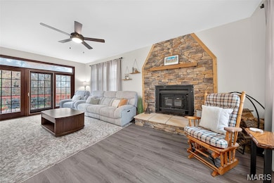 Living area with a fireplace, wood finished floors, and ceiling fan