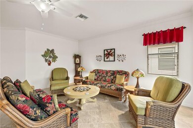 Living room featuring crown molding, tile floors, and ceiling fan