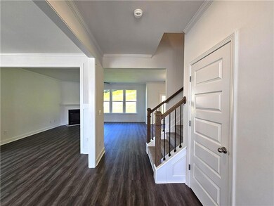 Foyer featuring crown molding, dark wood-style floors, a fireplace, and stairway