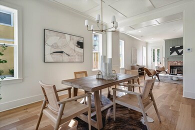 Dining area with a chandelier, crown molding, a brick fireplace, and light hardwood / wood-style floors