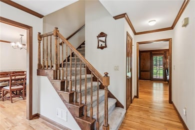 Staircase with crown molding, wood finished floors, a chandelier, and baseboards