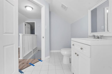 Bathroom featuring lofted ceiling, toilet, vanity,