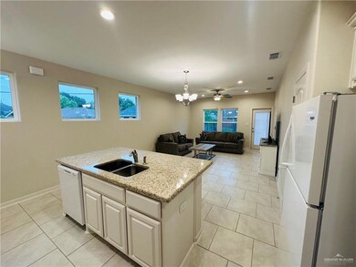 Kitchen with white appliances, a kitchen island with sink, white cabinets, sink, and light tile floors