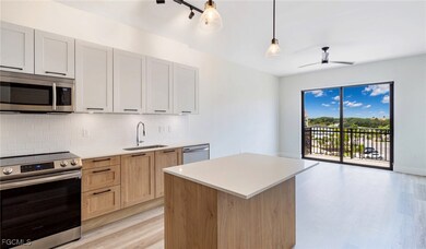 Kitchen with light wood-style floors, appliances with stainless steel finishes, light countertops, a sink, and backsplash