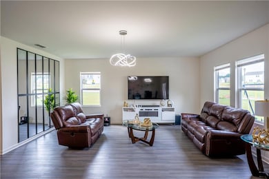 Living area with healthy amount of natural light, dark wood-style floors, and a chandelier