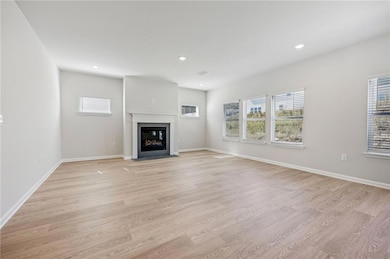 Unfurnished living room featuring plenty of natural light, light wood-type flooring, recessed lighting, and a fireplace with flush hearth