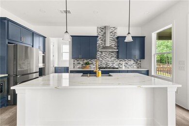 Kitchen with wall chimney exhaust hood, blue cabinetry, healthy amount of natural light, light wood-style floors, and recessed lighting