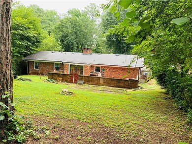 Back of house featuring a lawn, a chimney, and bri
