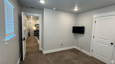 Unfurnished bedroom with dark carpet and baseboards