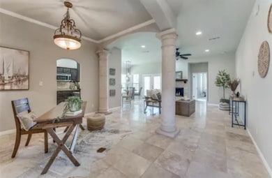 Dining area featuring ornate columns, arched walkways, recessed lighting, a fireplace, and a ceiling fan