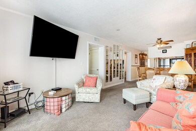 Carpeted living area with visible vents, crown mol