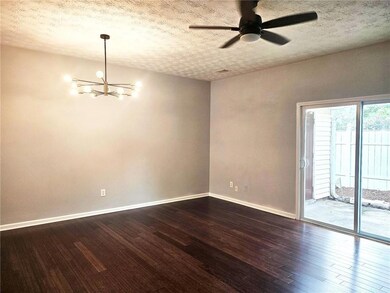 Spare room featuring a chandelier, a ceiling fan, a textured ceiling, and dark wood-style flooring