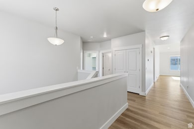 Hall with an upstairs landing, light wood-type flooring, and recessed lighting