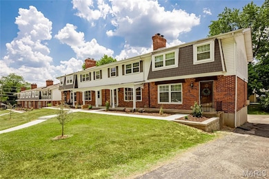 View of front of property with a chimney, brick siding, and a front lawn