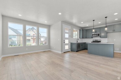 Kitchen with decorative backsplash, gray cabinetry, recessed lighting, decorative light fixtures, and light countertops