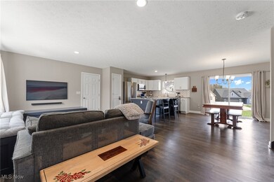 Living room with an inviting chandelier, dark wood finished floors, a textured ceiling, recessed lighting, and baseboards